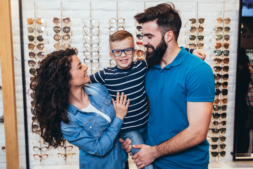 child and family at opticians fitted with glasses